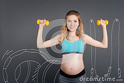 Cheerul pregnant woman using dumbbels Stock Photo