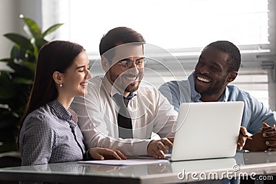 Cheery workers sitting at desk watching funny videos on laptop Stock Photo