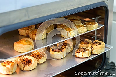 Cheese and bacon mini quiches on baking trays in commercial oven Stock Photo