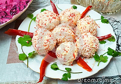 cheese balls made out of crab sticks on a plate, decorated with red pepper Stock Photo