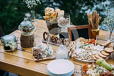 Cheese bar of several kinds of cheese, snacks, honey, nuts decorated on wooden table at the wedding party. Concept of Stock Photo