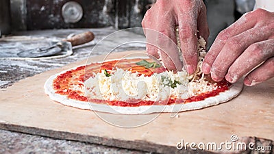 Cheese being spread on tomato sauce on pizza base. Stock Photo
