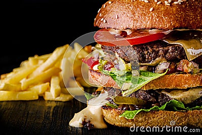 Cheese burger with grilled meat, cheese, tomato and potatoes on dark wooden surface. Ideal for advertisement. Close-up Stock Photo