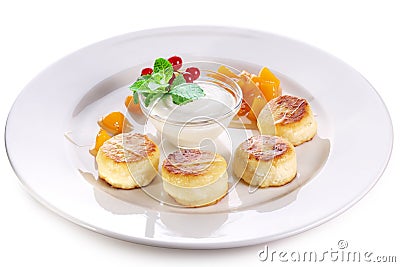 Cheese cakes with sour cream, slices of sweet peach, mint and red currants on a white plate. Clipping path Stock Photo