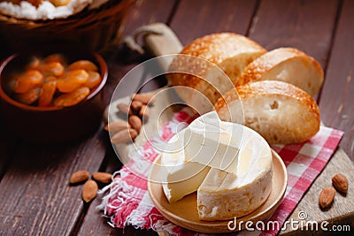 Cheese camembert or brie with bagette, nuts and dried apricots served on wooden board Stock Photo