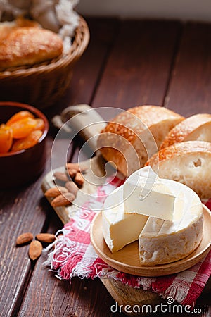 Cheese camembert or brie with bagette, nuts and dried apricots served on wooden board Stock Photo