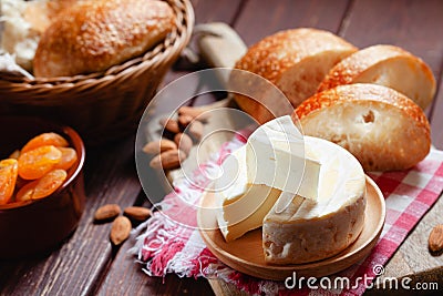 Cheese camembert or brie with bagette, nuts and dried apricots served on wooden board Stock Photo