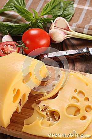 Cheese on a cutting board, basil, tomato Stock Photo