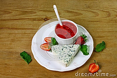 Cheese dourble or brie with blue mold with strawberry jam and mint on a white plate, wooden background. Food for wine and romantic Stock Photo