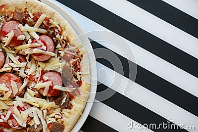 Close up of freshly home made pizza on a white plate with cheese, meat, onions, spicy products. Italian traditional food Stock Photo