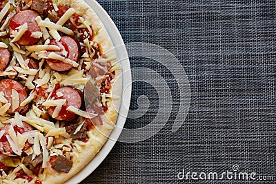 Close up of freshly home made pizza on a white plate with cheese, meat, onions, spicy products. Italian traditional food Stock Photo