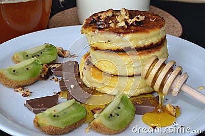 cheese pancakes, chocolate and kiwi lie on a white plate Stock Photo