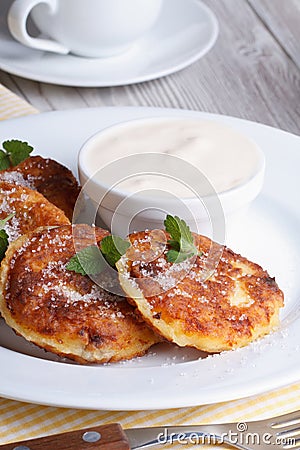 Cheese pancakes on a white plate with sour cream vertical Stock Photo