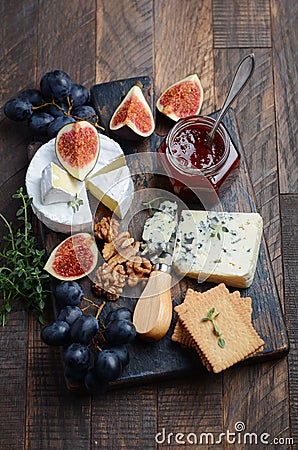 Cheese plate with grapes, figs, crackers, honey, plum jelly, thyme and nuts. Stock Photo