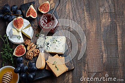 Cheese plate with grapes, figs, crackers, honey, plum jelly, thyme and nuts. Stock Photo
