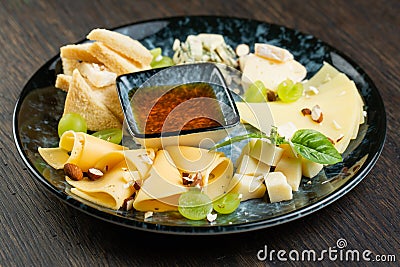 Cheese plate with green grapes, crunchy croutons and nuts. set of different types of cheese with honey on a marble plate Stock Photo