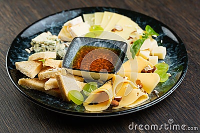 Cheese plate with green grapes, crunchy croutons and nuts. set of different types of cheese with honey on a marble plate Stock Photo