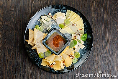 Cheese plate with green grapes, crunchy croutons and nuts. set of different types of cheese with honey on a marble plate. view Stock Photo