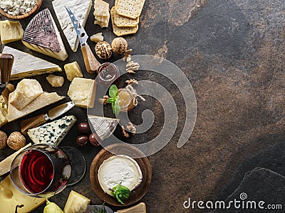 Cheese platter with organic cheeses, fruits, nuts and wine on stone background. Top view. Tasty cheese starter Stock Photo