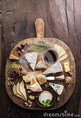 Cheese platter with organic cheeses, fruits, nuts and wine on wooden background. Top view. Tasty cheese starter Stock Photo