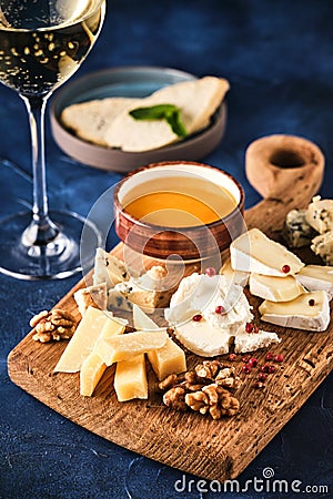 Cheese set with honey and nuts. Assortment of cheeses on a wooden board. Cheese appetizer set Stock Photo