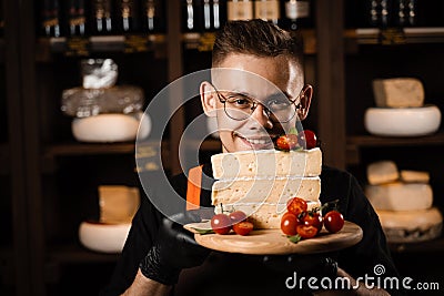 Cheese Sommelier holding plate with brie cheese with tomatoes. Creative idea for advertising a cheese shop. Stock Photo