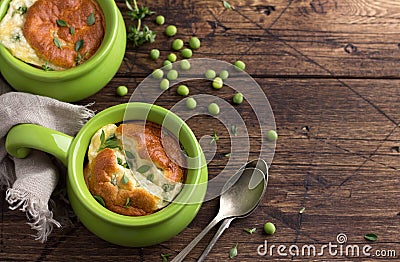 Cheese souffle with young peas flavored with thyme in portion molds on a wooden table Stock Photo