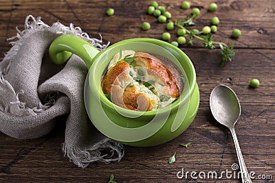 Cheese souffle with young peas flavored with thyme in portion molds on a wooden table Stock Photo