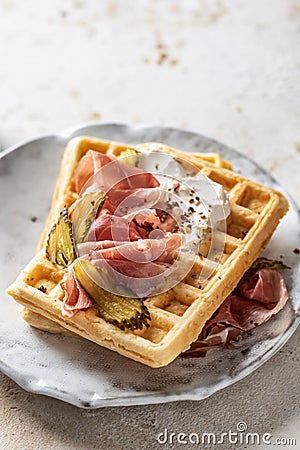 Cheese waffles with ham, cream cheese and cucumber close up. Delisious savory breakfast Stock Photo