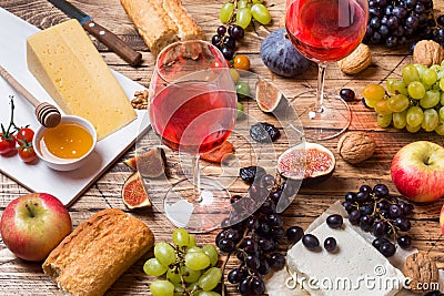 Cheese, wine, baguette grapes figs honey and snacks on the rustic wooden table top. Stock Photo