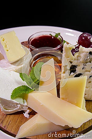 Cheeseboard. Parmesan, blue cheese, Camembert served with mint, honey, jam, grapes on a wooden board Stock Photo