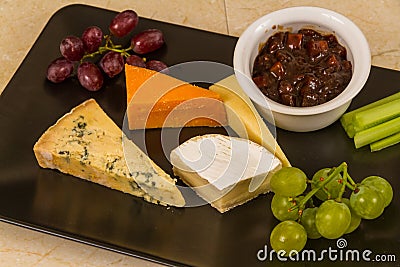 Cheeseboard platter with grapes and pickle Stock Photo