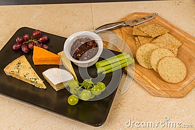 Cheeseboard platter with grapes and pickle and crackers Stock Photo