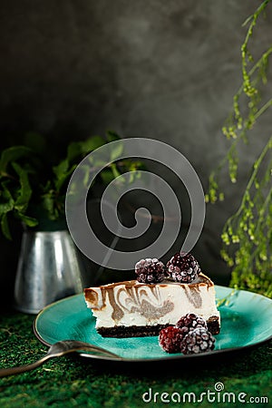 Cheesecake with chocolate flavor is on a plate with blackberries In the background a bank with mint Stock Photo