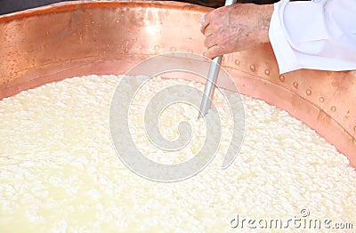 Cheesemaker stirs the curds into the copper cauldron to make che Stock Photo