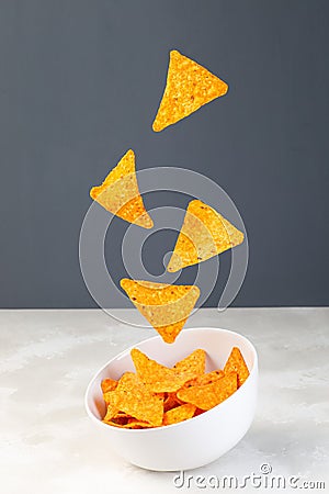 Cheesy tortilla chips or nacho levitate above the bowl, vertical Stock Photo