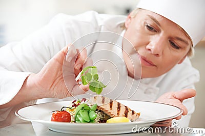 Chef Adding Garnish To Meal In Restaurant Kitchen Stock Photo