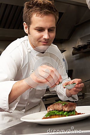 Chef Adding Seasoning To Dish In Restaurant Stock Photo