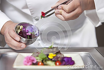 Chef Arranging Edible Flowers On Salad Stock Photo