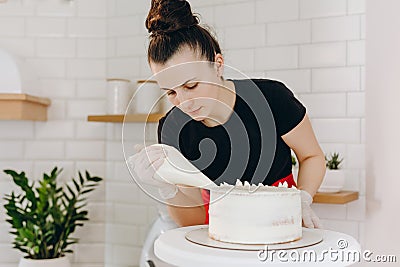 Chef or baker decorating cake with white whipped cream. Stock Photo