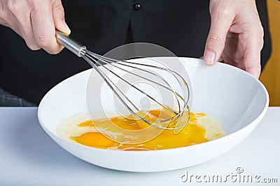 Chef beating eggs in a bowl witha a manual mixer Stock Photo