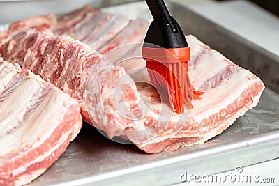 Chef brushing raw beef ribs with marinade Stock Photo