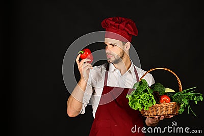 Chef in burgundy uniform holds red pepper in hand. Stock Photo