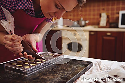 Chef chocolatier squeezing filling of creamy liquid preparing luxury handmade chocolate pralines at home kitchen Stock Photo