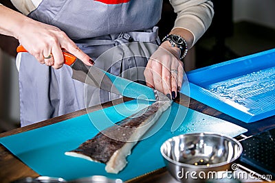 Chef cleans fish from scales. Master class in the kitchen. The process of cooking. Step by step. Tutorial. Close-up Stock Photo