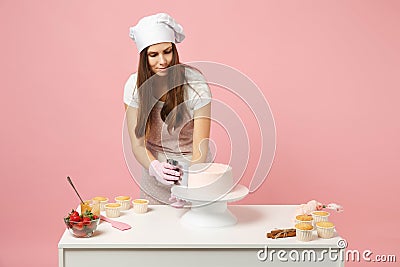 Chef cook confectioner or baker in white t-shirt toque chefs hat cooking at table isolated on pink pastel background in Stock Photo