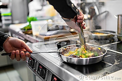 Chef cook hand cooking potato and meat food in pan Stock Photo