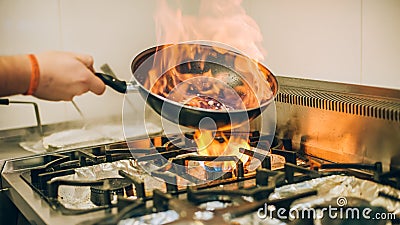 Chef cook prepares meal in flame fire burn frying pan Stock Photo