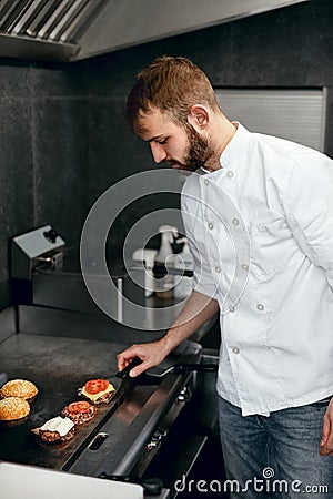 Chef Cooking Burgers in Kitchen Stock Photo