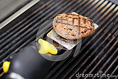 Chef cooking a hamburger patty on a grill Stock Photo
